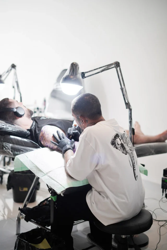 Tattoo artist in black gloves working at a station covered in protective film at Mason's Ink
