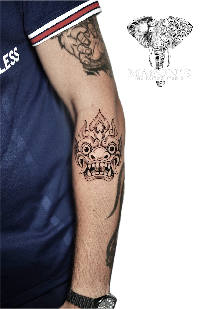 Barong Tattoo Design: a detailed demon face with flames and ornamental patterns on the forearm