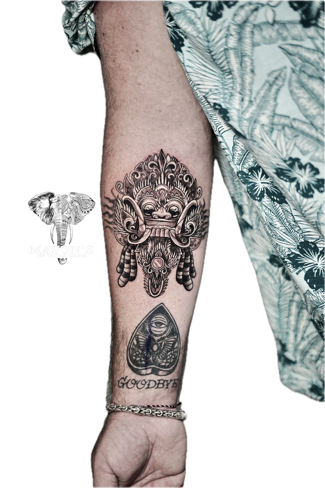 Balinese Barong Tattoo Design: a large forearm tattoo of a mask with intricate geometric patterns and lettering