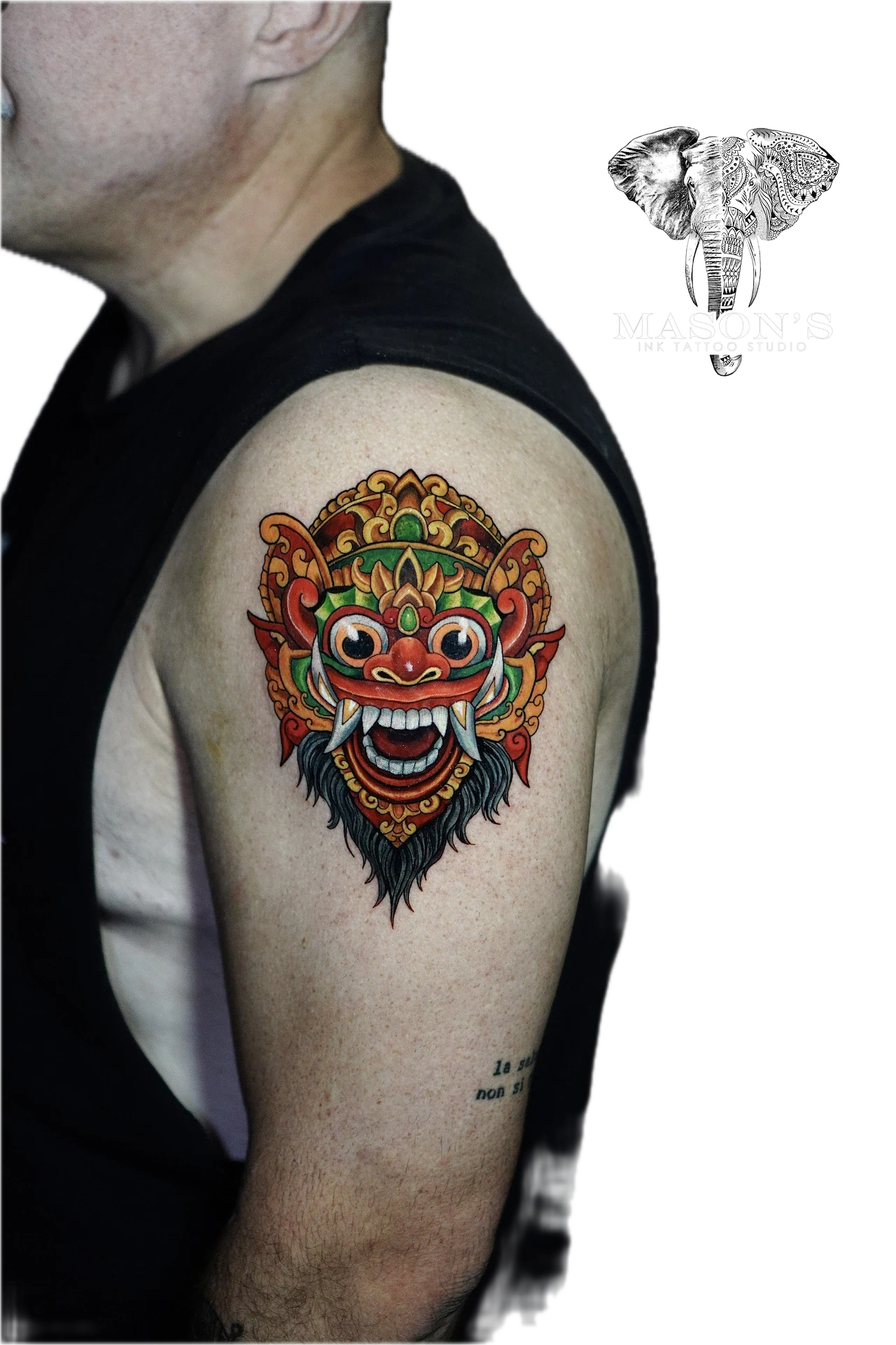 Colored Barong Tattoo Design: a colorful ornamental mask tattoo on the upper arm