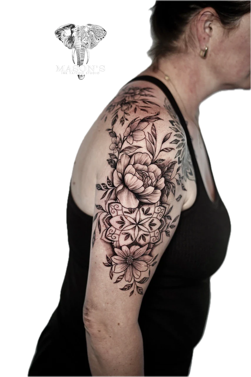 Black and Grey Flower Tattoo Design: a large floral mandala with roses and leaves on the upper arm