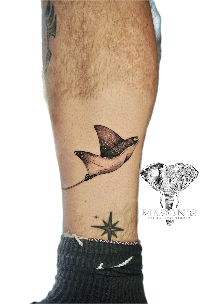 Black and Grey Manta Ray Tattoo Design: a small black and grey bat tattoo on the calf with a star