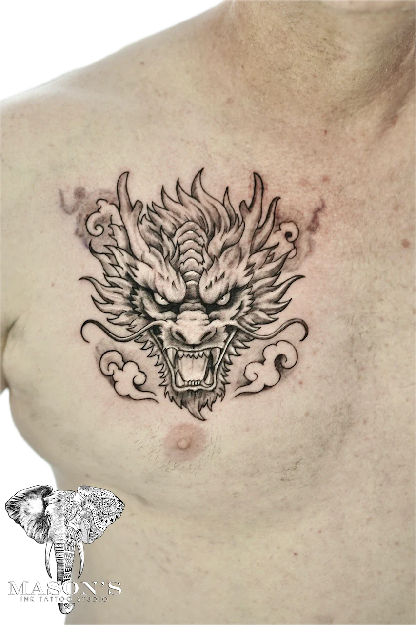 Black and Grey Dragon Tattoo Design: a detailed dragon head tattoo on the chest