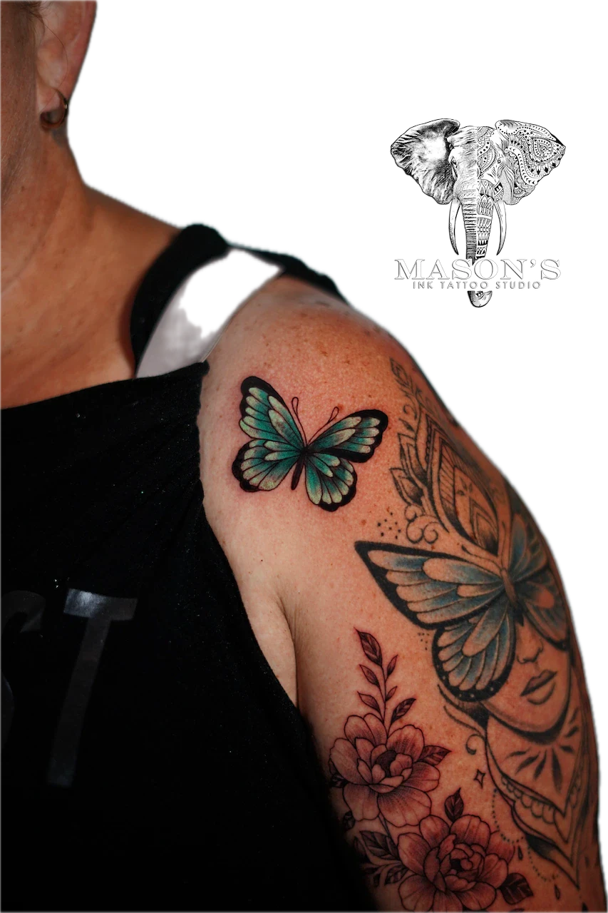 Black and Grey Woman Floral Butterfly Tattoo Design: Two butterflies with flowers and leaves on an upper arm