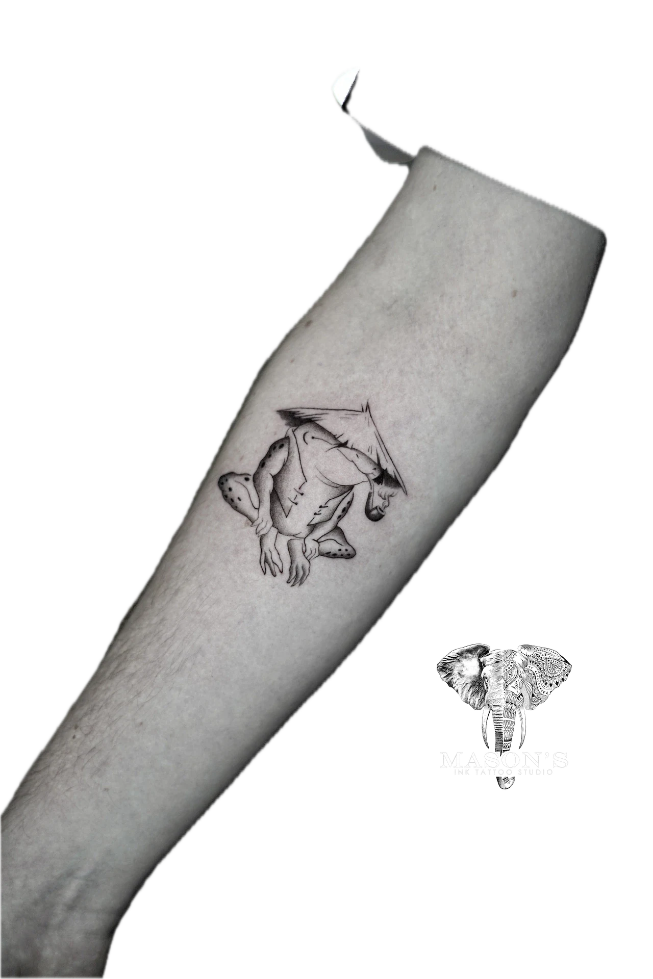 Black and Grey Frog Tattoo Design: a small black and grey tattoo of a baby elephant wearing a hat
