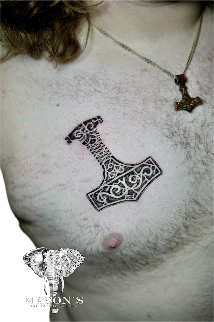 Blackwork Tattoo Design: a small black and grey hammer tattoo with intricate lettering on a chest