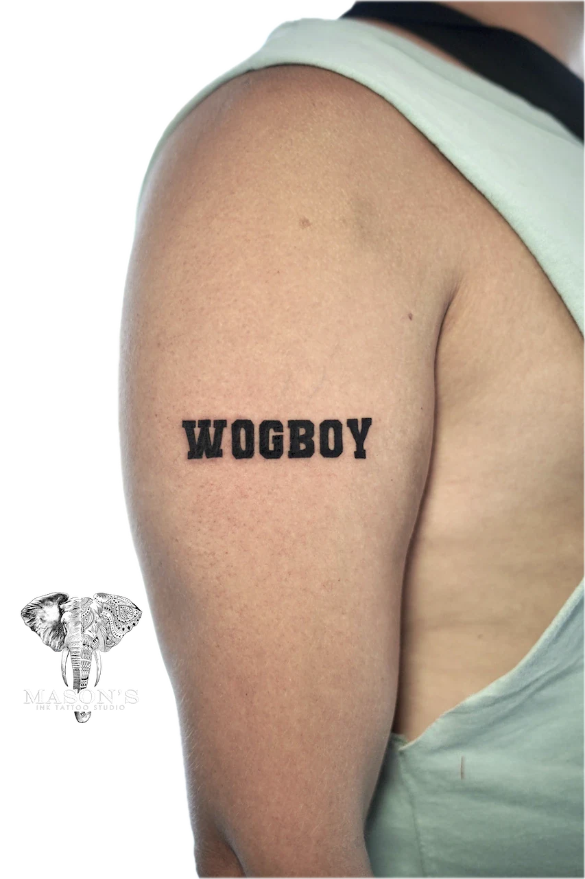 Blackwork Bold Script Tattoo Design: Black lettering tattoo on the upper arm