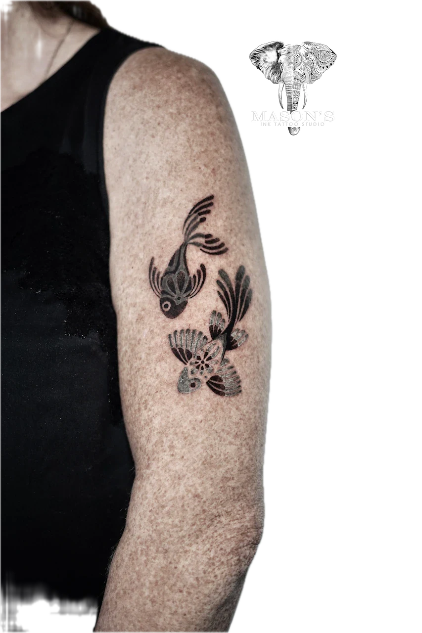 Blackwork Ornamental Fish Tattoo Design: Two fish swimming among plants on an upper arm