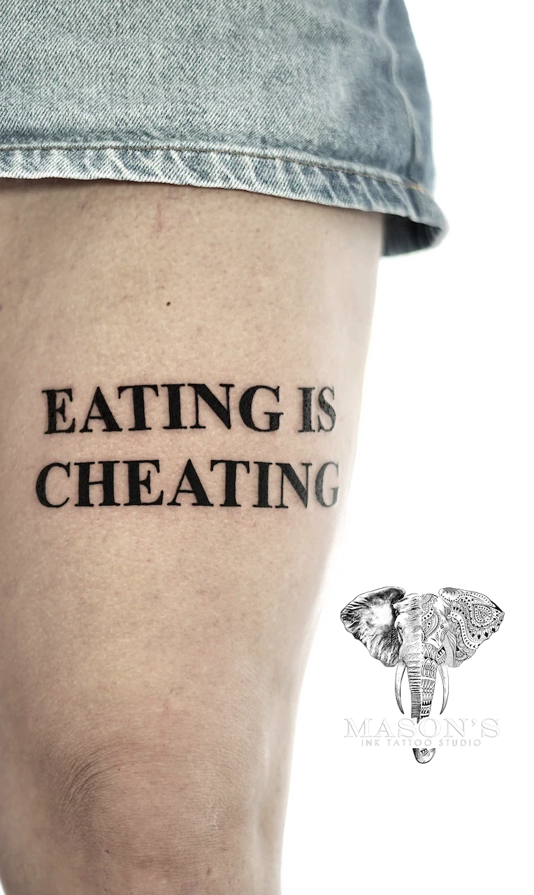 Blackwork Script Tattoo Design: Black and grey lettering tattoo on thigh