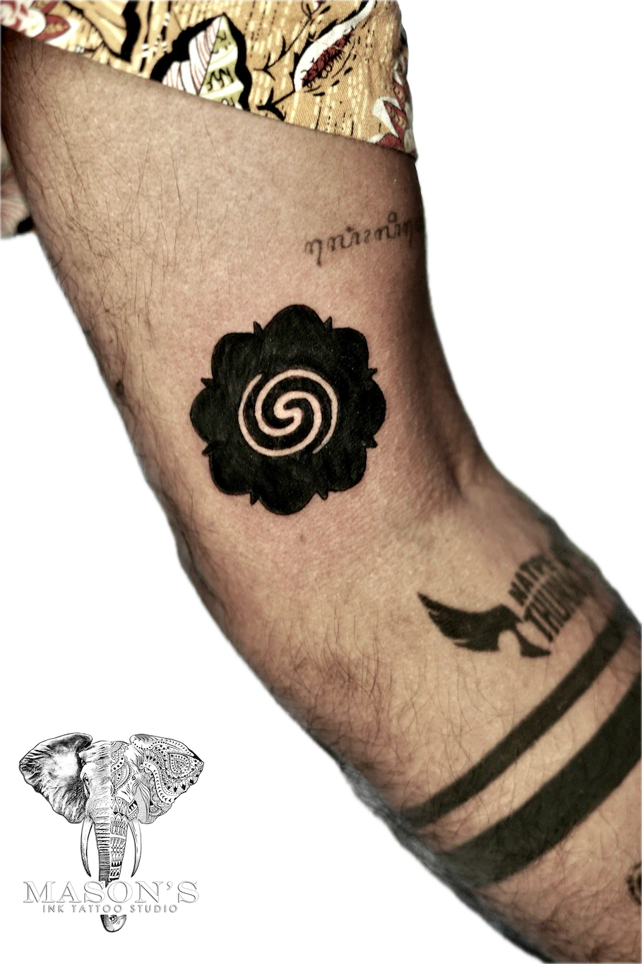 Blackwork Tattoo Design: a small black and grey spiral flower tattoo on the forearm