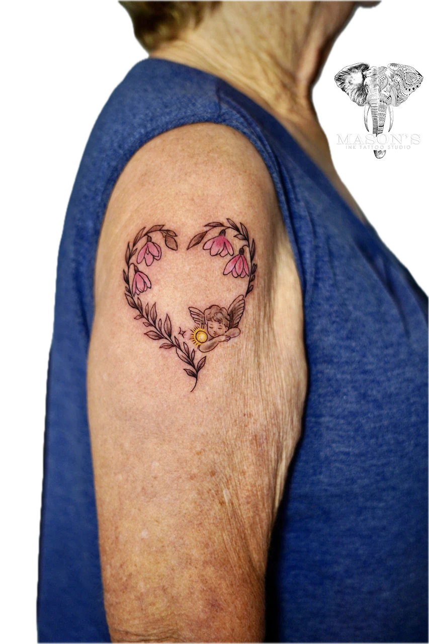 Fine Line Color Flower Tattoo Design: a sleeping angel inside a heart of flowers on the upper arm