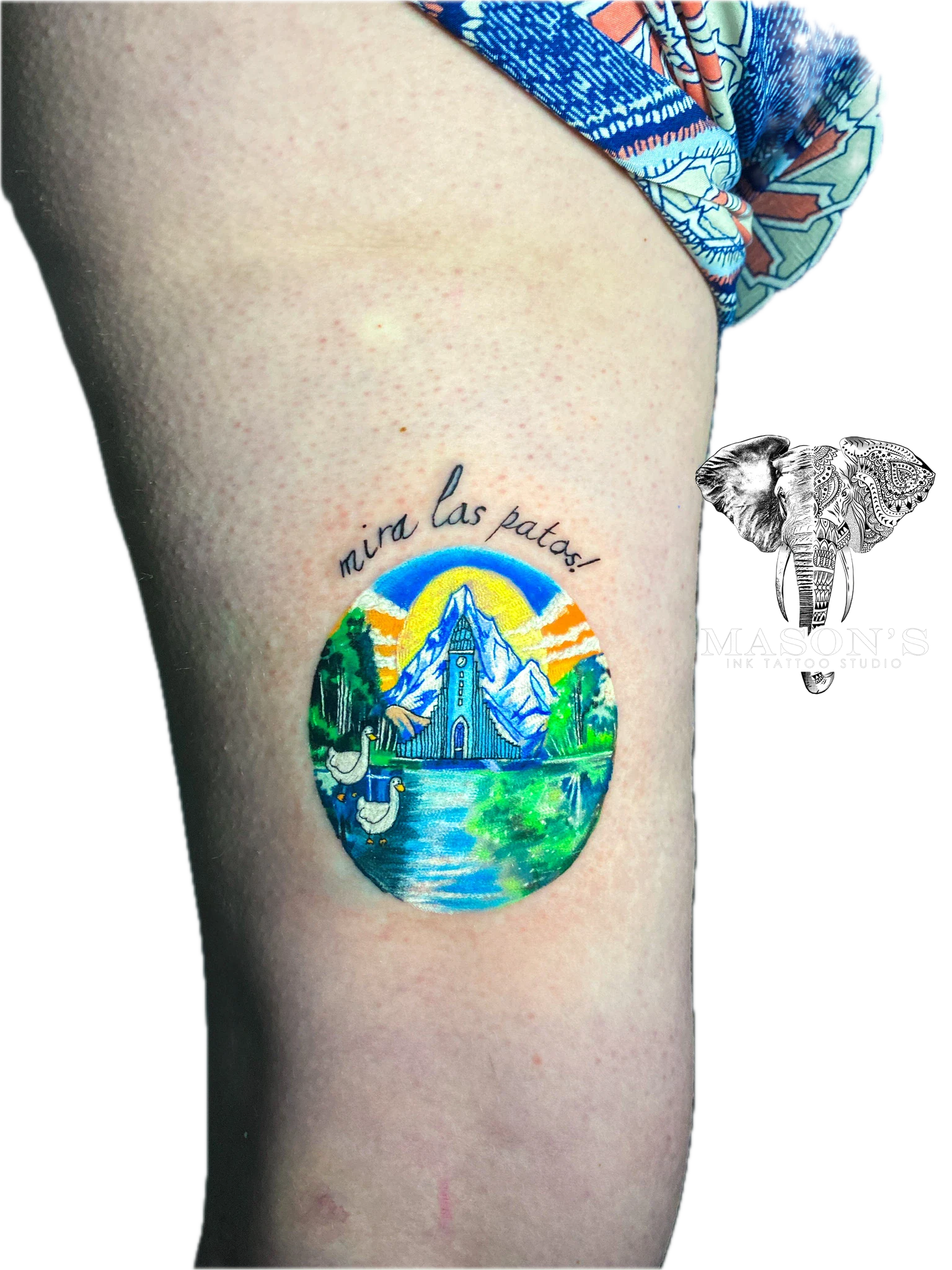 Color Tattoo Style Mountains Design: a colorful scene with a swan, castle, and text on a thigh