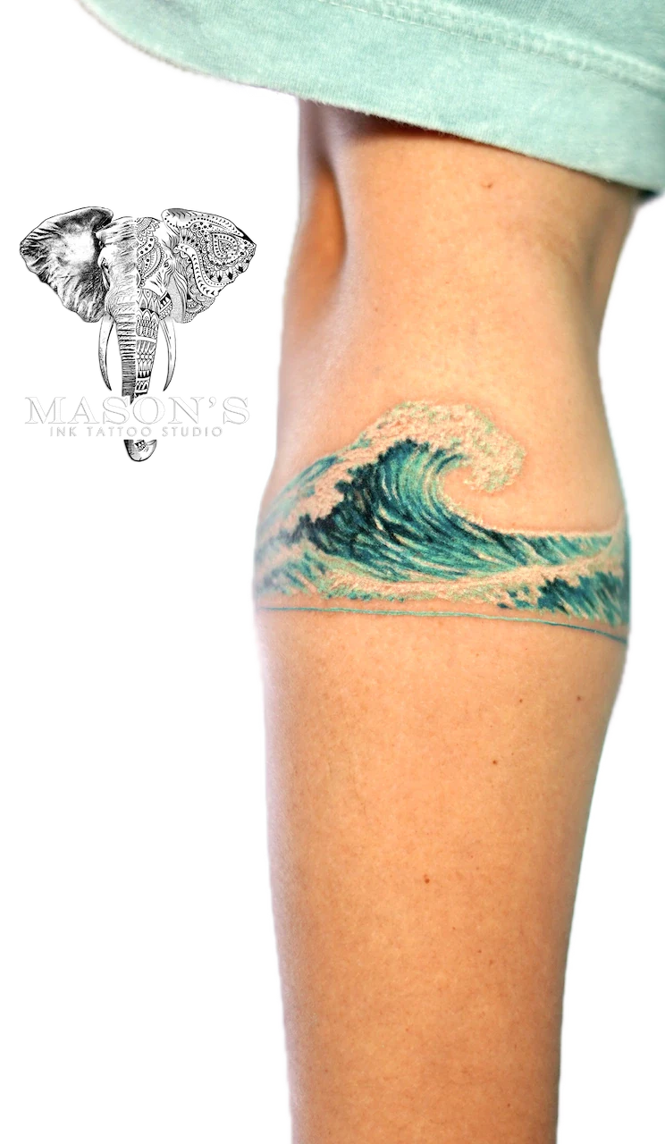Color Realism Wave Armband Tattoo Design: a wave tattoo on the thigh with sand and water details