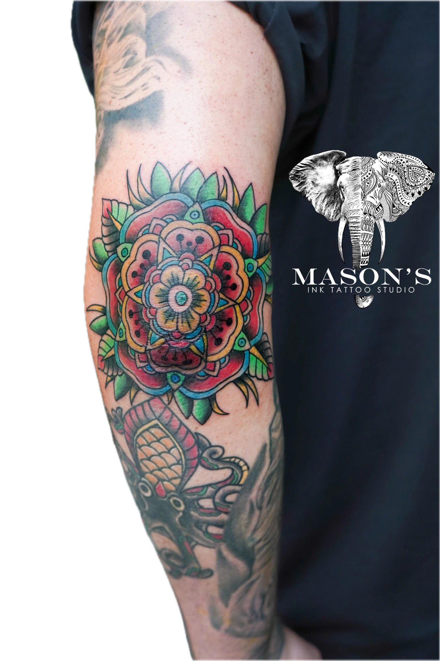 Colored Traditional Tattoo Design: a colorful mandala with a flower and eye in the center on a forearm