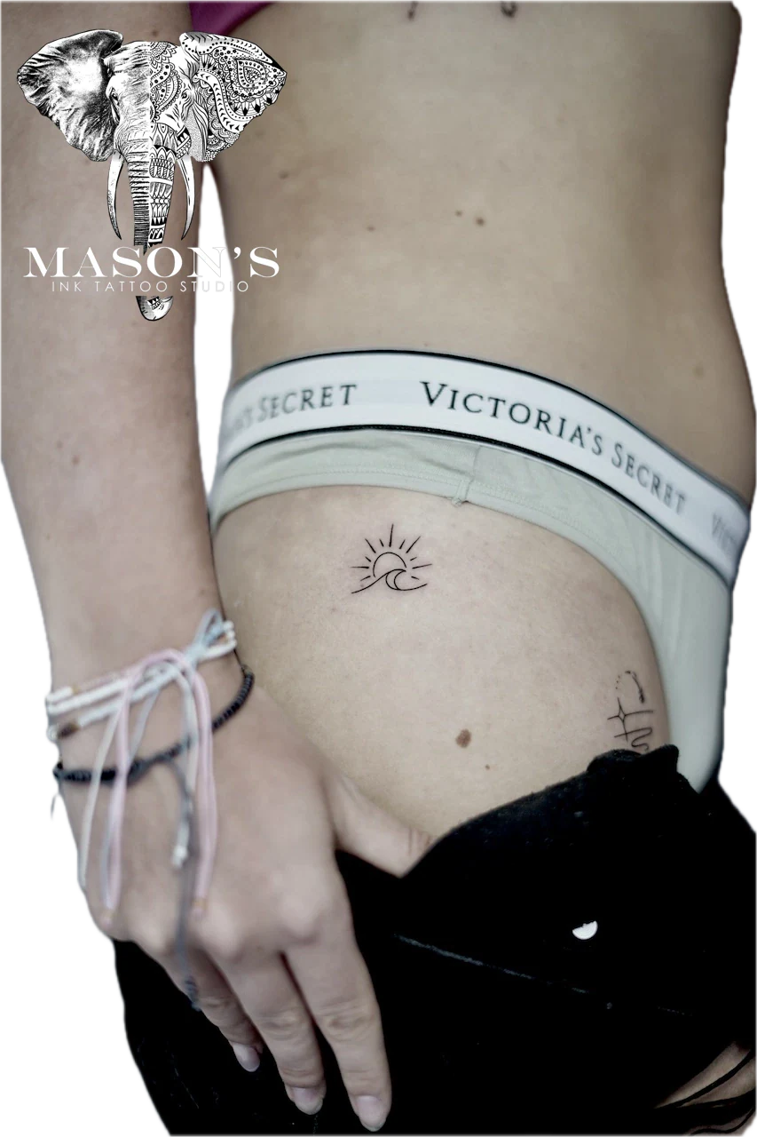 Fine Line Sun and Wave Tattoo Design: a minimal sun and moon crescent tattoo with lettering on the hip