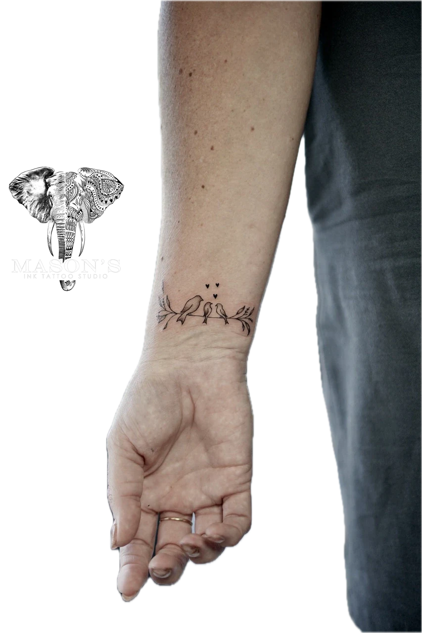 Fine Line Bird Outline Tattoo Design: Two birds on a branch with hearts and leaves on a wrist