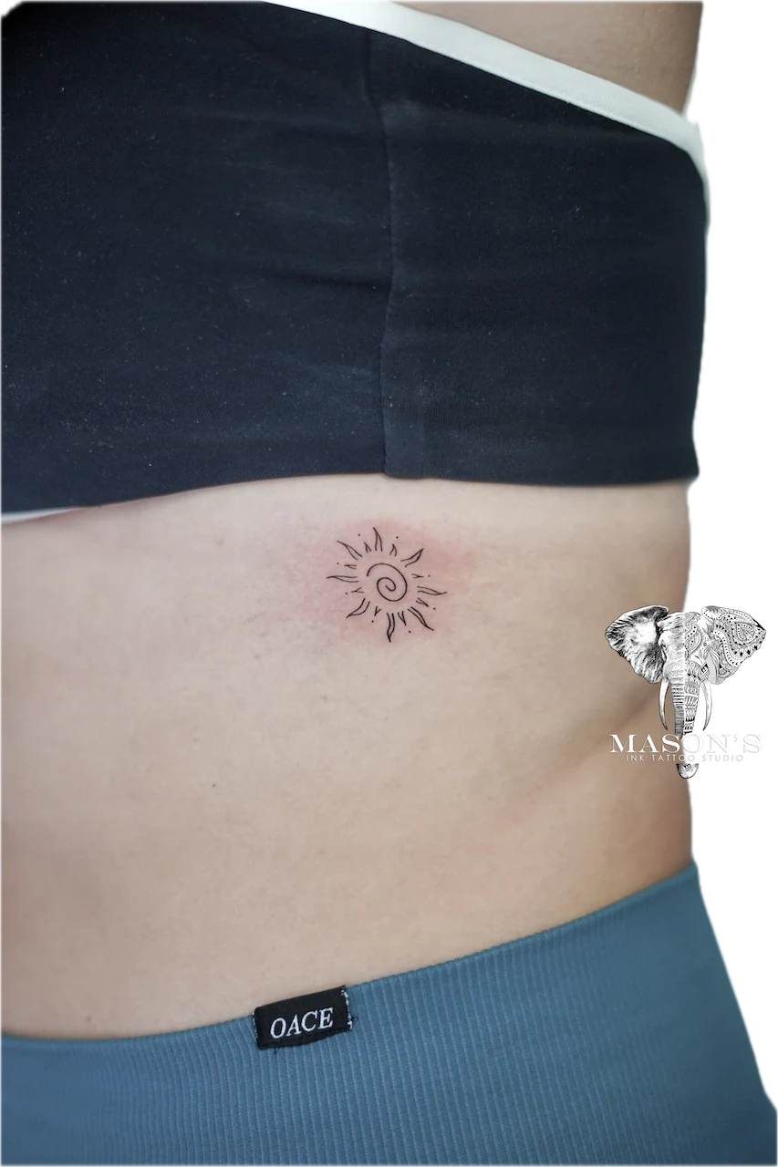 Fine Line Sun Tattoo Design: a minimalist sun tattoo on the stomach