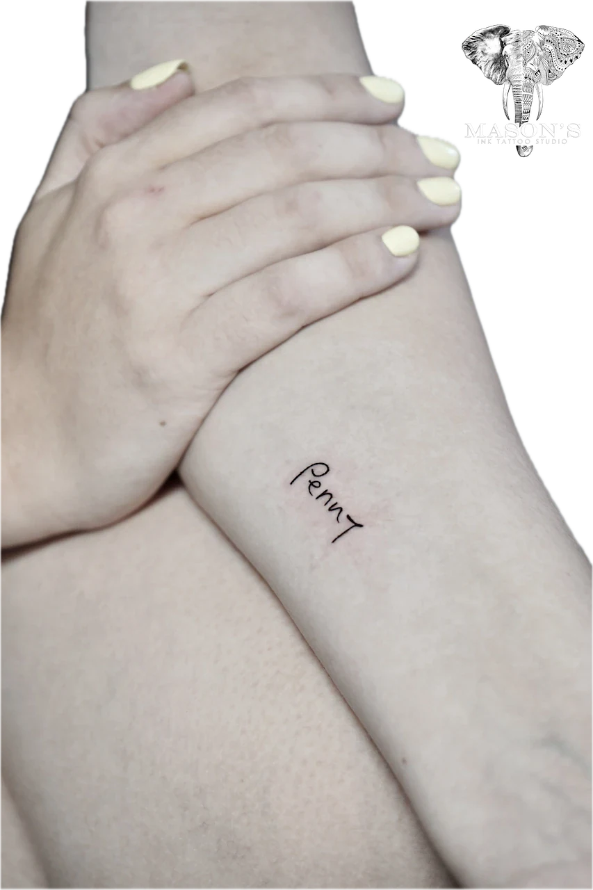 Fine Line Script Tattoo Design: Small wrist tattoo of the name 'Penny' in cursive