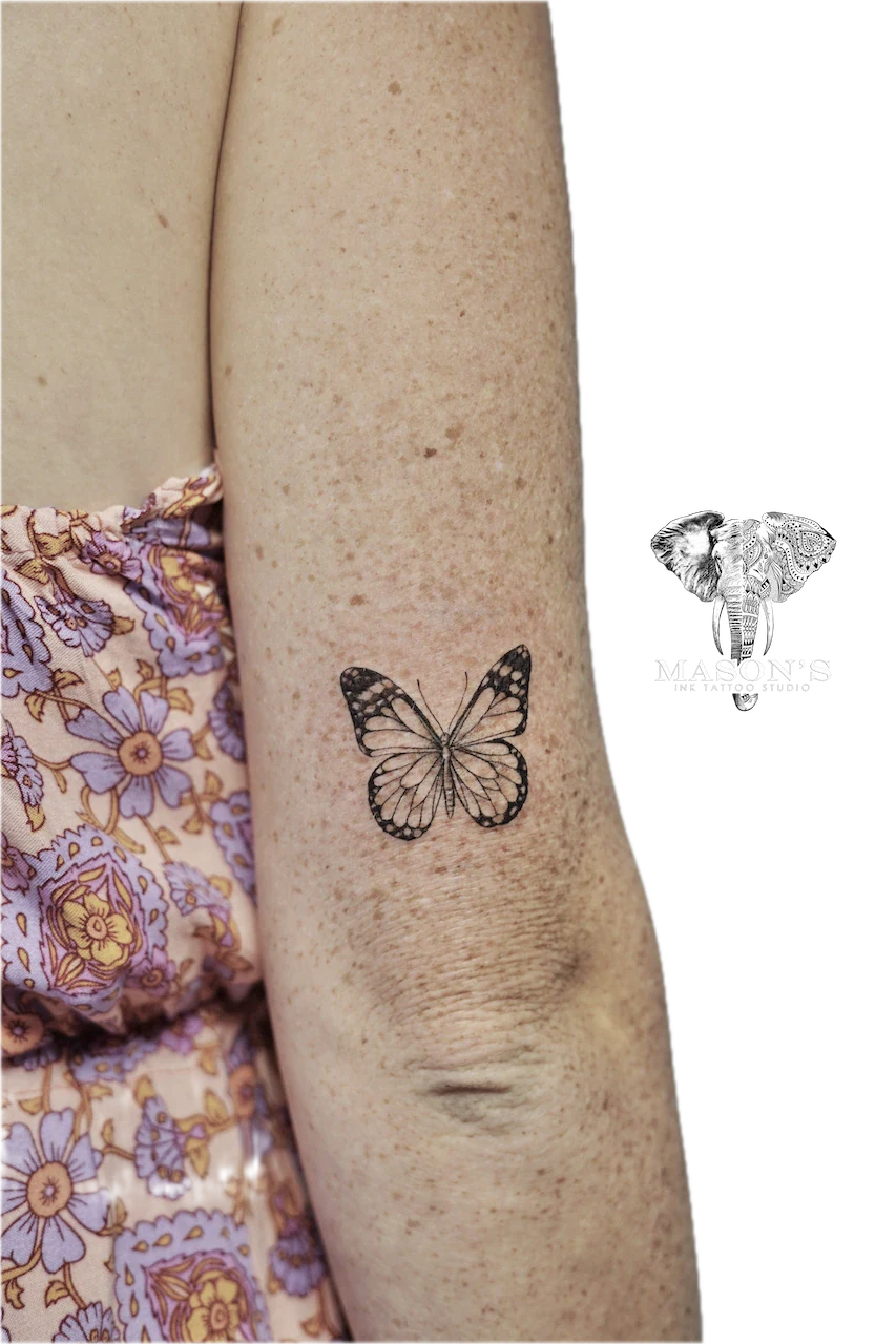 Fine Line Butterfly Tattoo Design: a small black and grey butterfly tattoo on the forearm