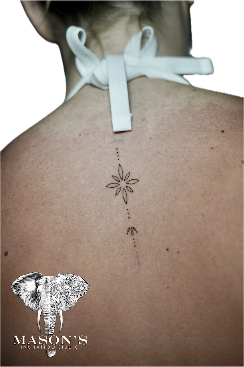 Fine Line Tattoo Design: a small flower with dots and a line on the spine