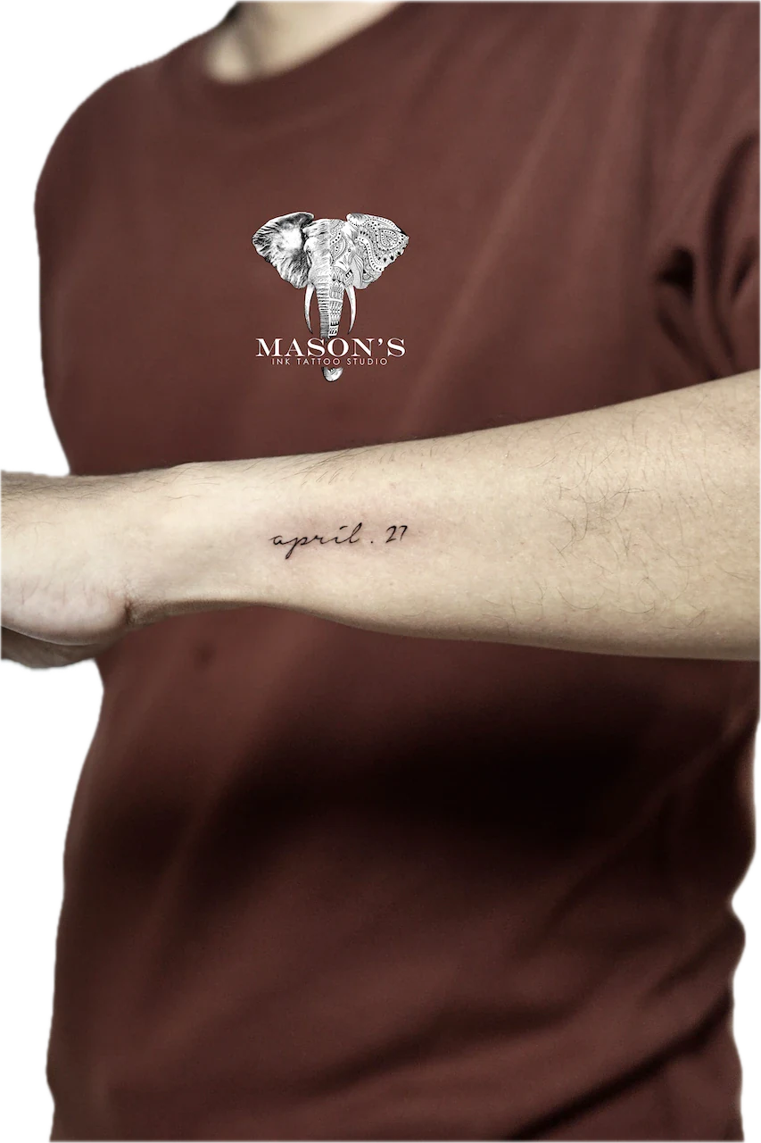 Fine Line Script Tattoo Design: Minimalist elephant logo and date on forearm