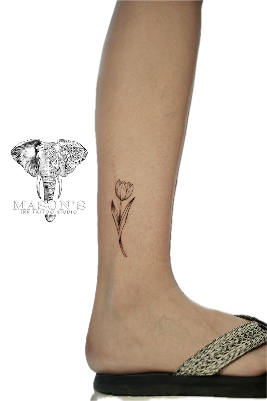 Fine Line Floral Tattoo Design: a simple black and grey tulip on the calf