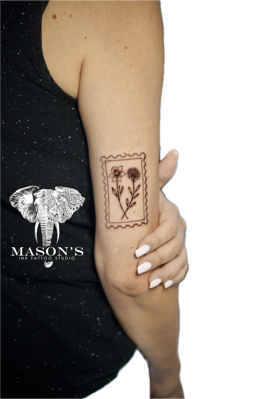 Fine Line Floral Tattoo Design: a minimalist floral design inside a stamp border on the forearm