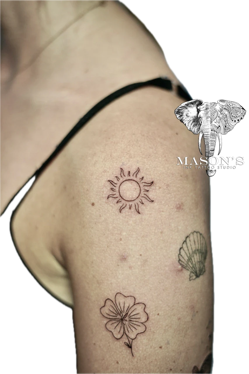 Fine Line Sun Tattoo Design: Minimalist sun, flower, and shell tattoos on the upper arm