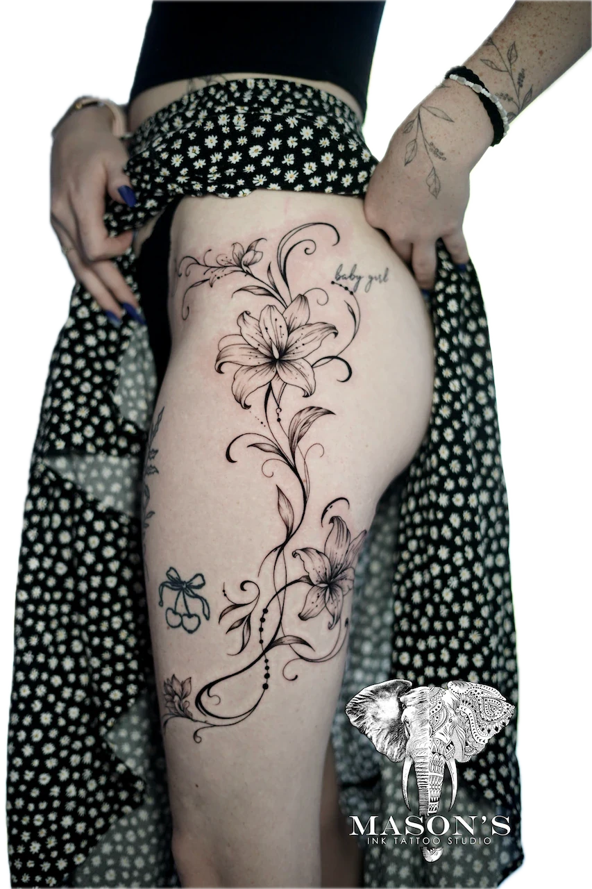 Fine Line Floral Tattoo Design: a large floral vine with lettering on the thigh