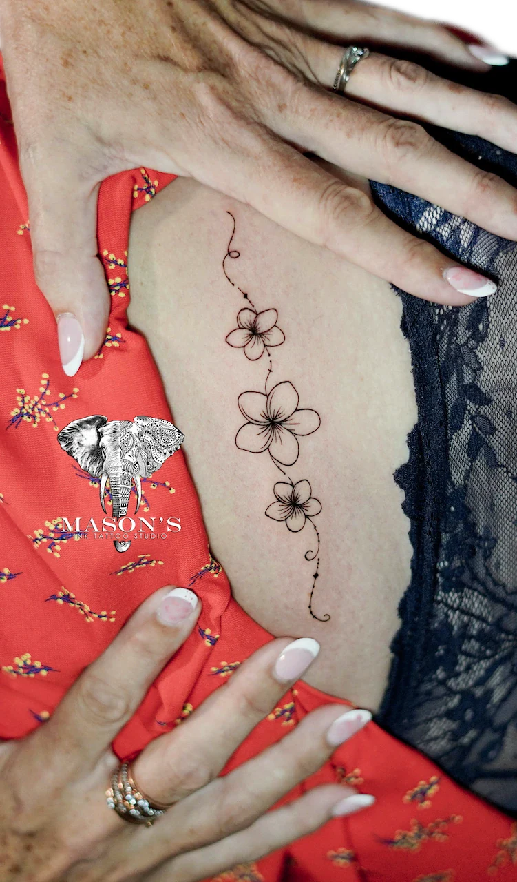 Fine Line Flower Tattoo Design: a minimalist floral vine tattoo on the ribs