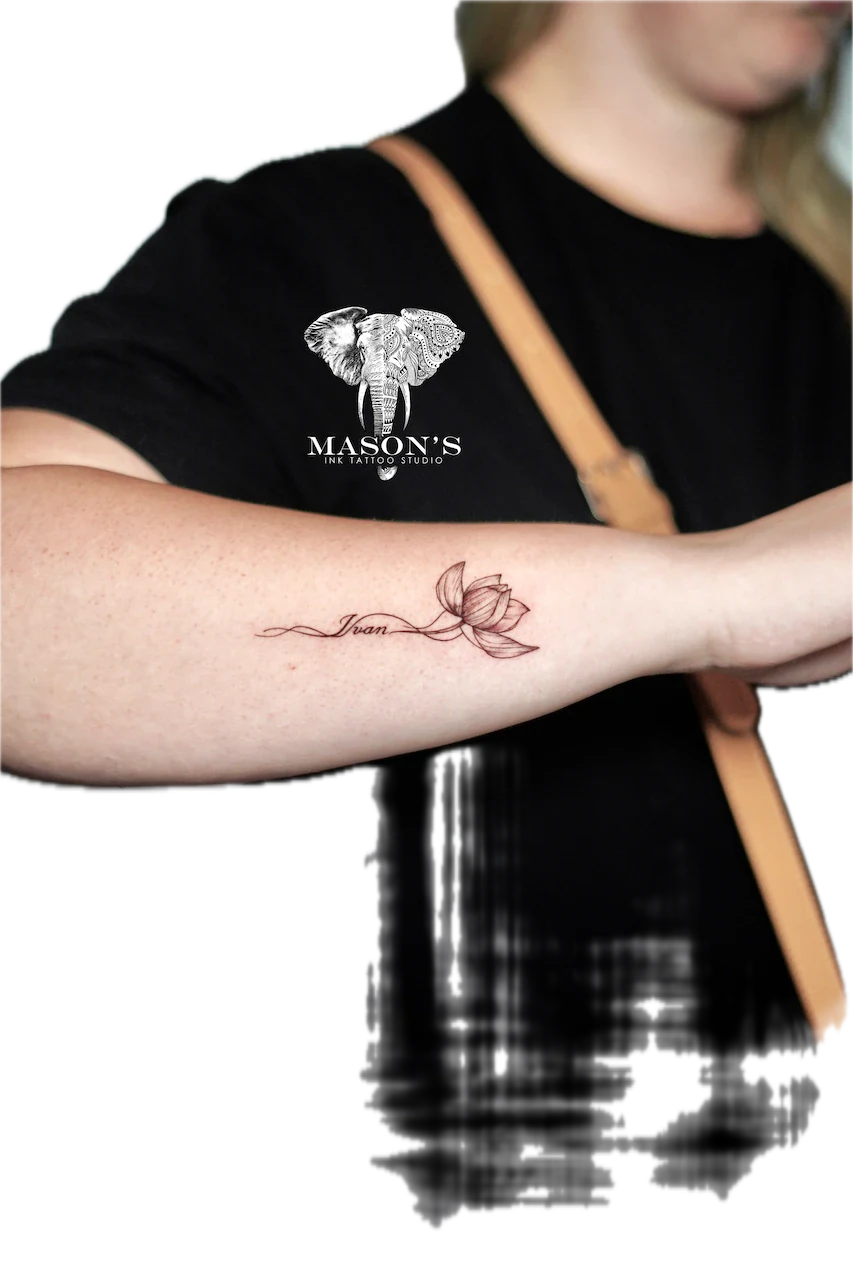 Fine Line Flower Tattoo Design: a small lotus flower with lettering on a forearm