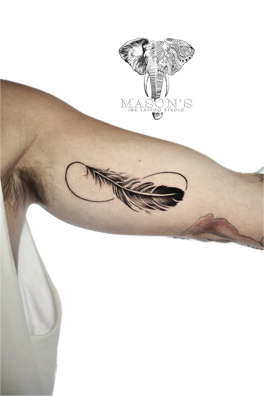 Fine Line Infinity Tattoo Design: a minimalist feather and heart tattoo on the upper arm