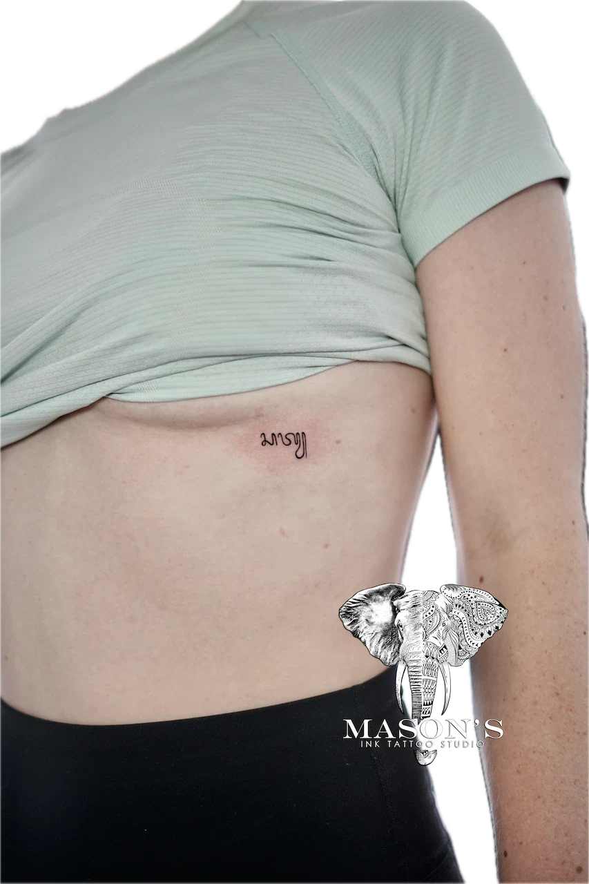 Fine Line Aksara Script Tattoo Design: Small minimal lettering tattoo on the hip