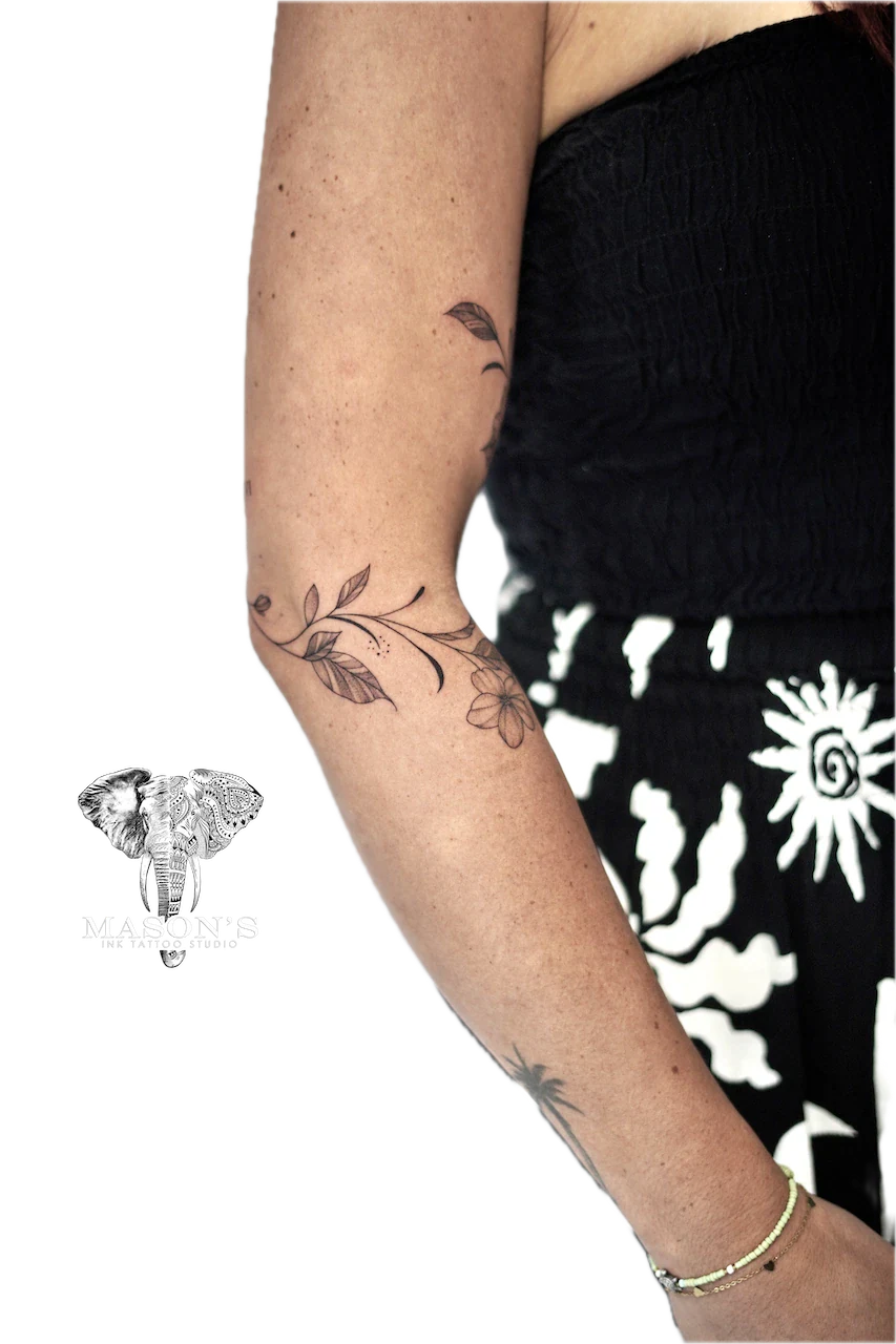 Fine Line Round Flower Tattoo Design: a delicate leaf and flower vine on the forearm
