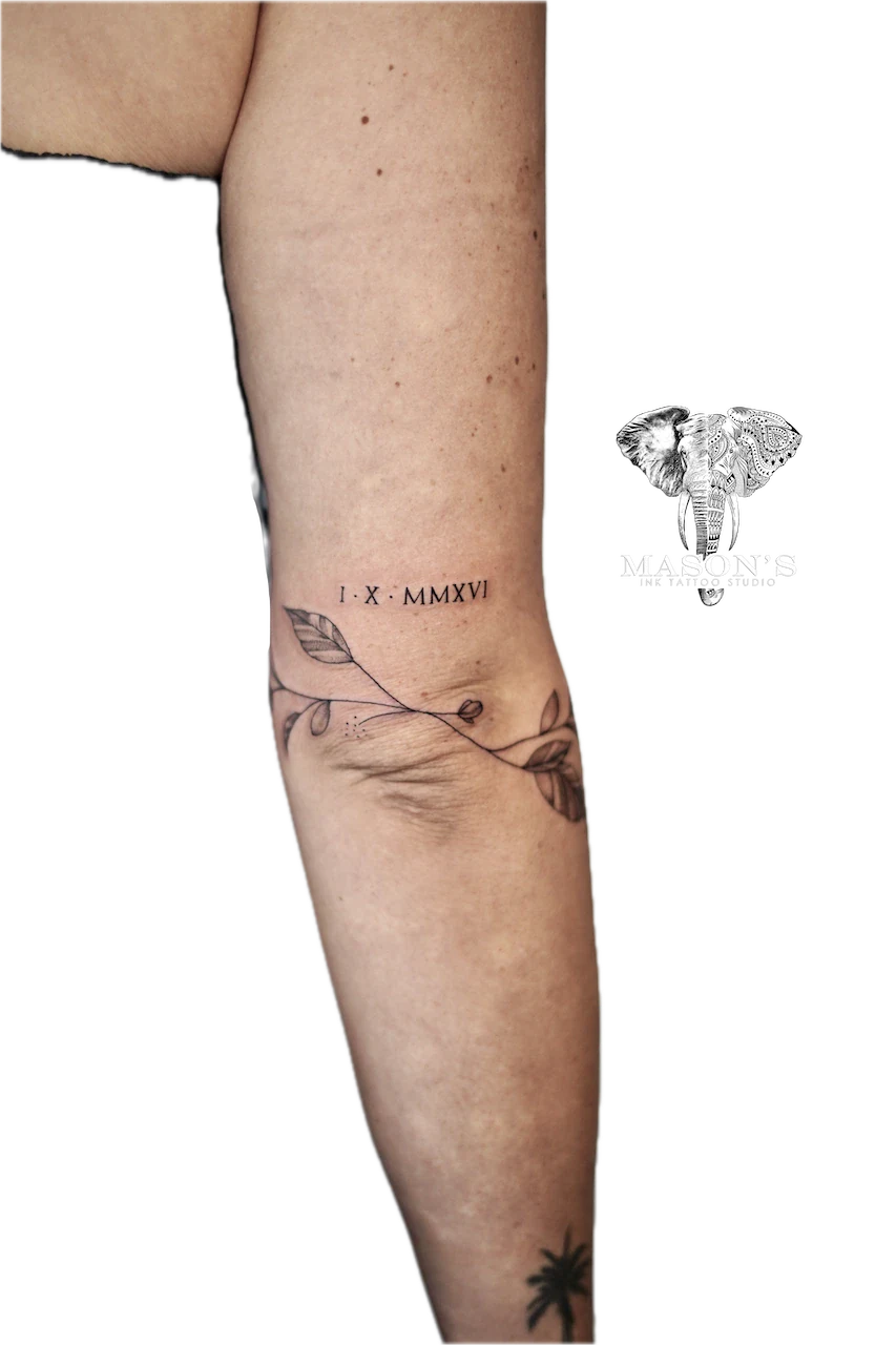 Fine Line Round Flower Tattoo Design: Minimalist leaf and berry branch with roman numerals on calf