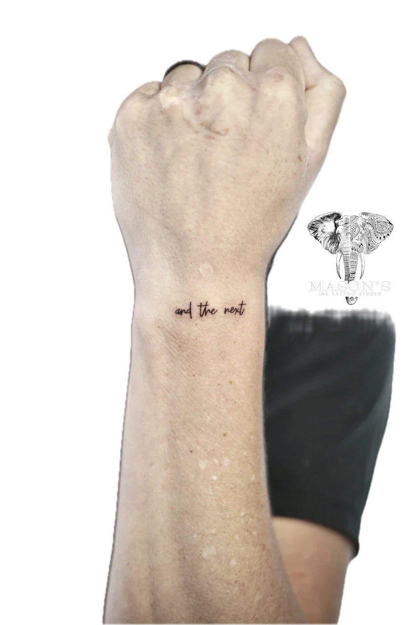 Fine Line Script Hand Tattoo Design: a small forearm tattoo of the phrase 'and the next'