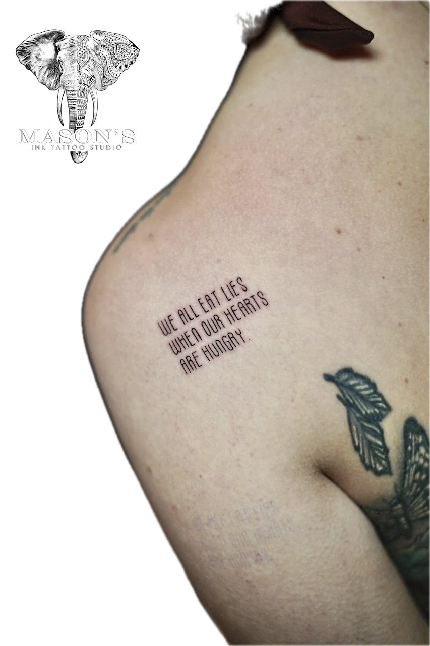 Fine Line Script Tattoo Artwork: Minimal script lettering on upper arm with a small wing