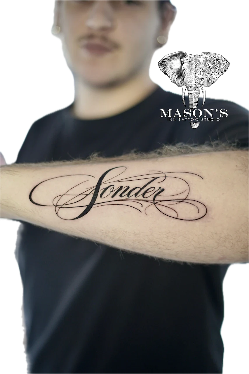 Fine Line Script Tattoo Design: Cursive lettering with swirls on the forearm