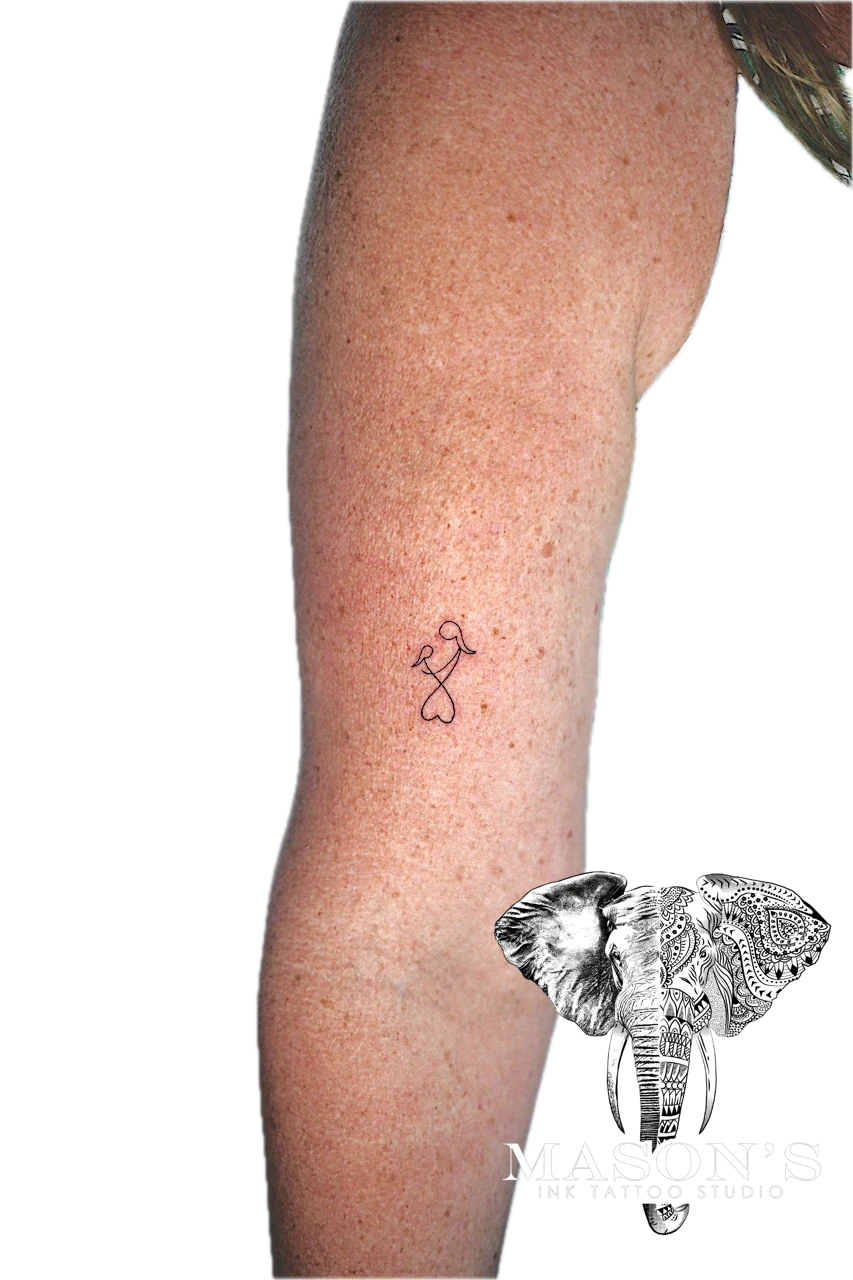 Fine Line Tattoo Design: a small heart and ribbon knot tattoo on the calf