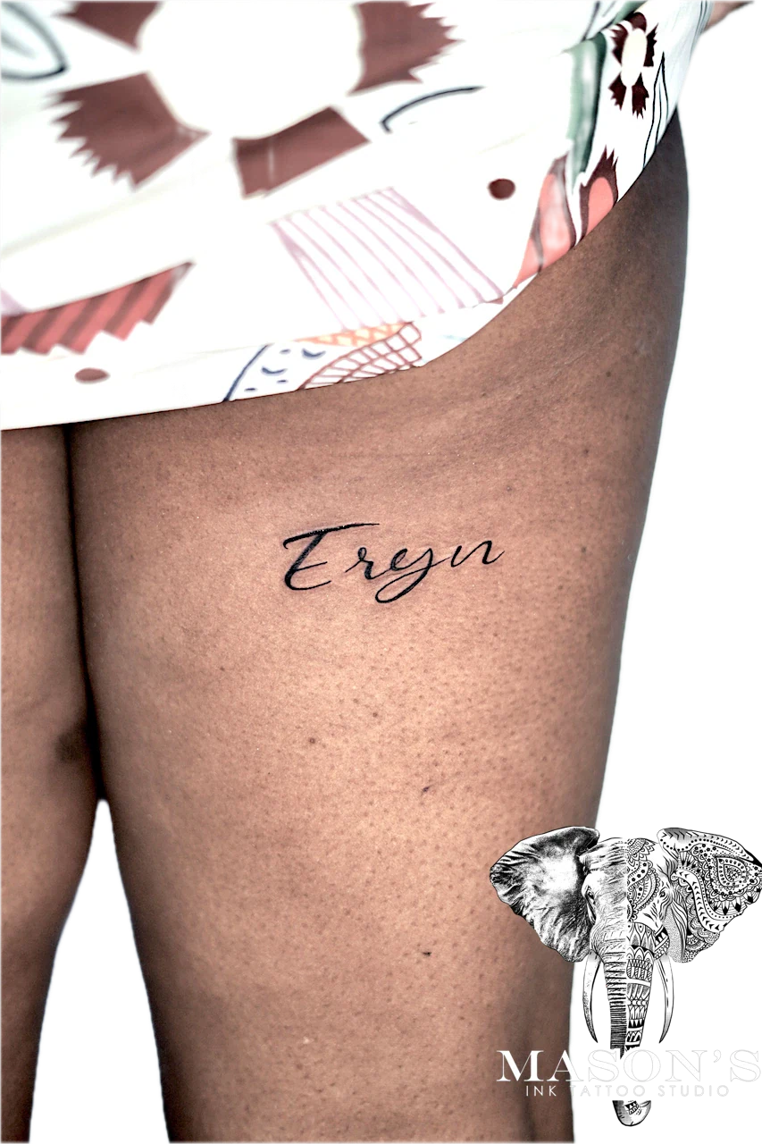 Fineline Script Tattoo Design: a small name tattoo on the thigh