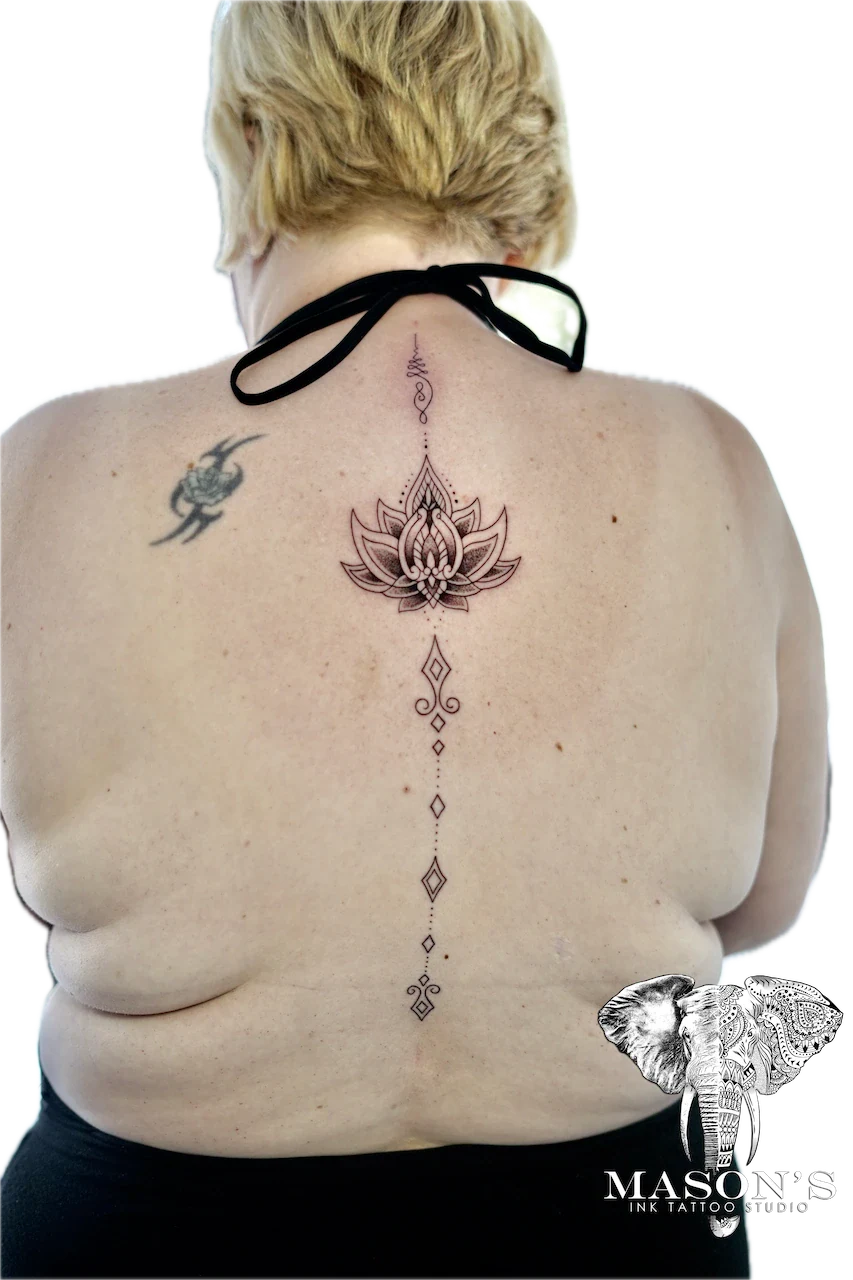 Minimalist Fine Line Tattoo Design: a lotus mandala with geometric patterns down the spine