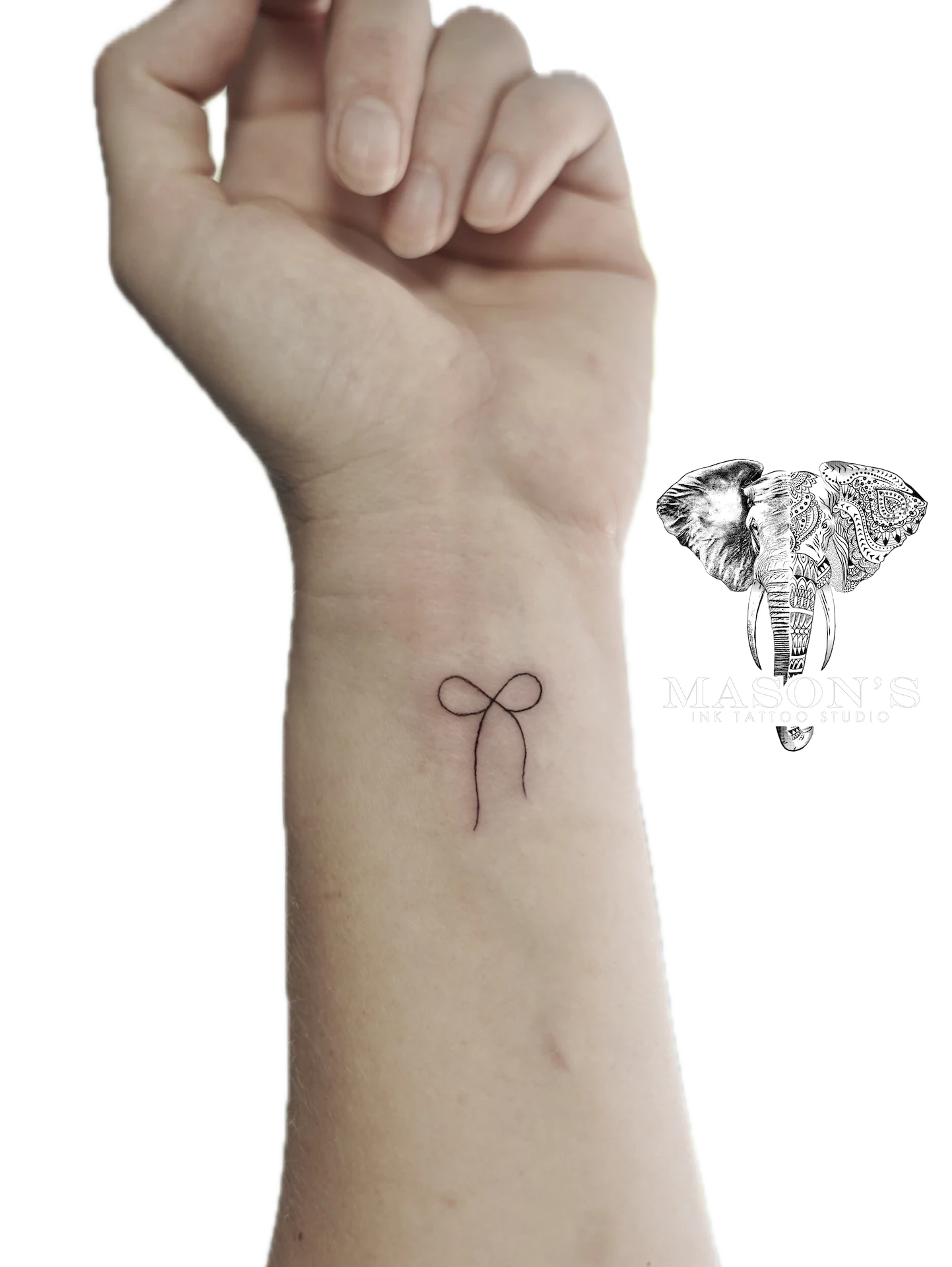 Black and Grey Fine Line Ribbon Tattoo: a small minimalist bow tattoo on the forearm