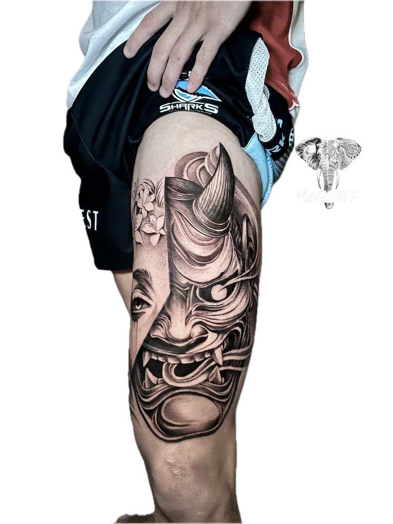 Japanese Hannya Mask Tattoo Design: a large black and grey thigh tattoo of a mythological face with waves