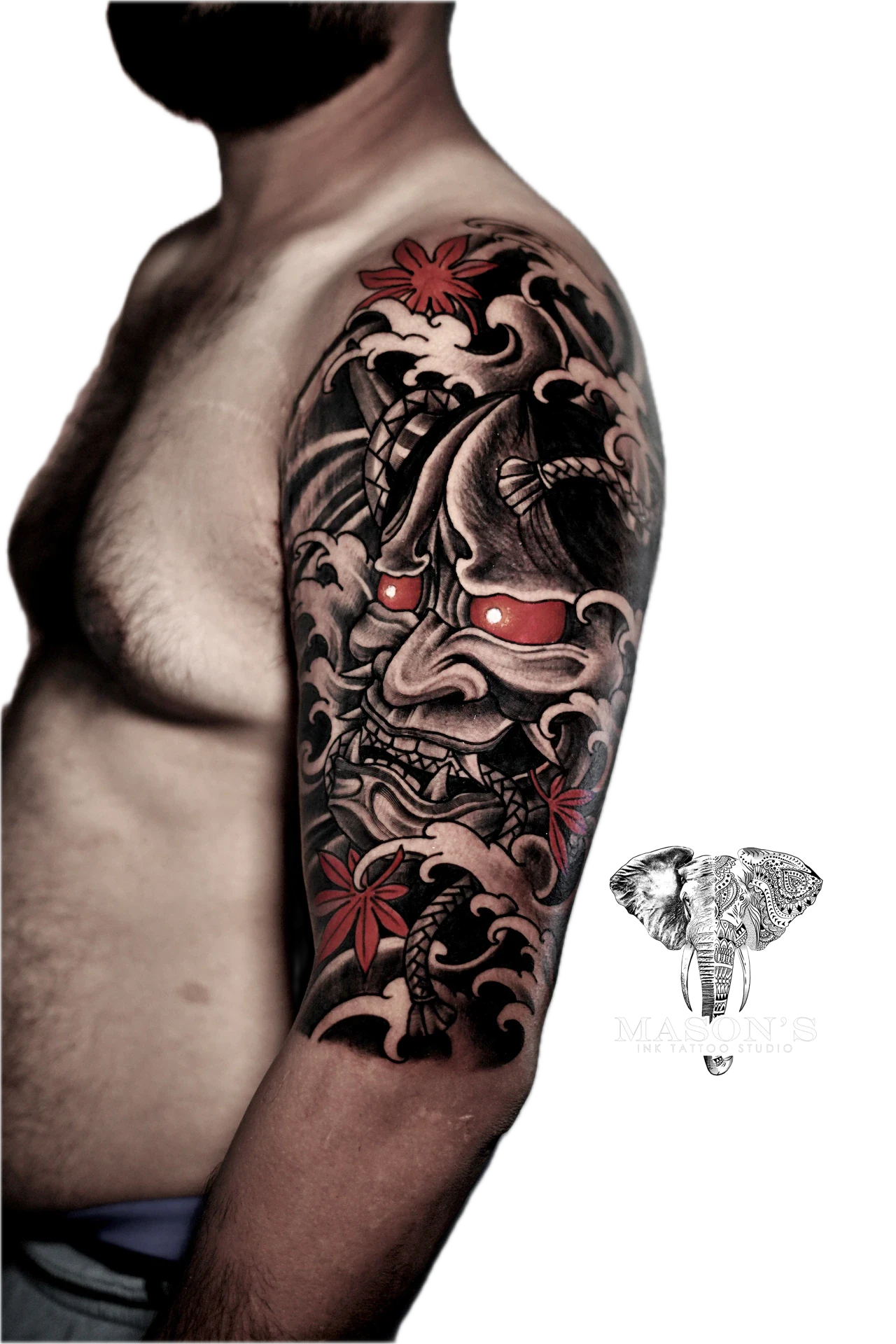 Japanese Tattoo Design: a large Japanese mask tattoo with flowers and waves on an upper arm