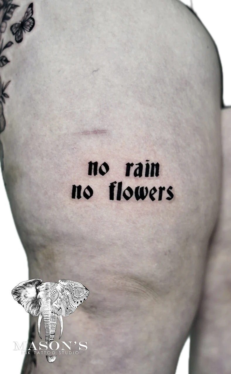 Script Lettering Tattoo Design: Minimalist lettering tattoo with butterfly and flower on ribs