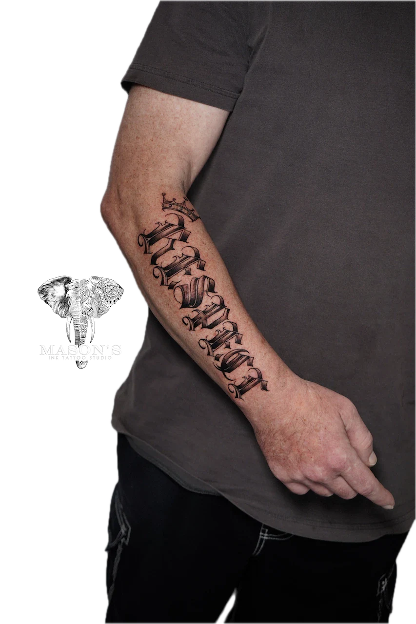 Script Lettering Tattoo Design: Elegant lettering with a crown on a forearm