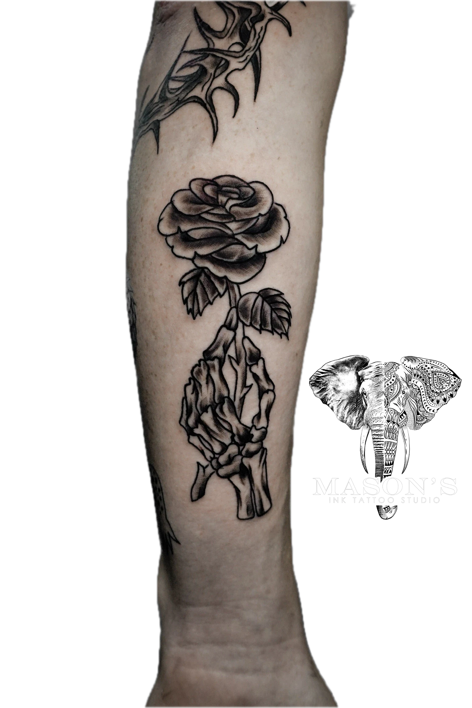 Traditional Skull and Rose Tattoo Design: a black and grey rose with a hand and bone on a forearm